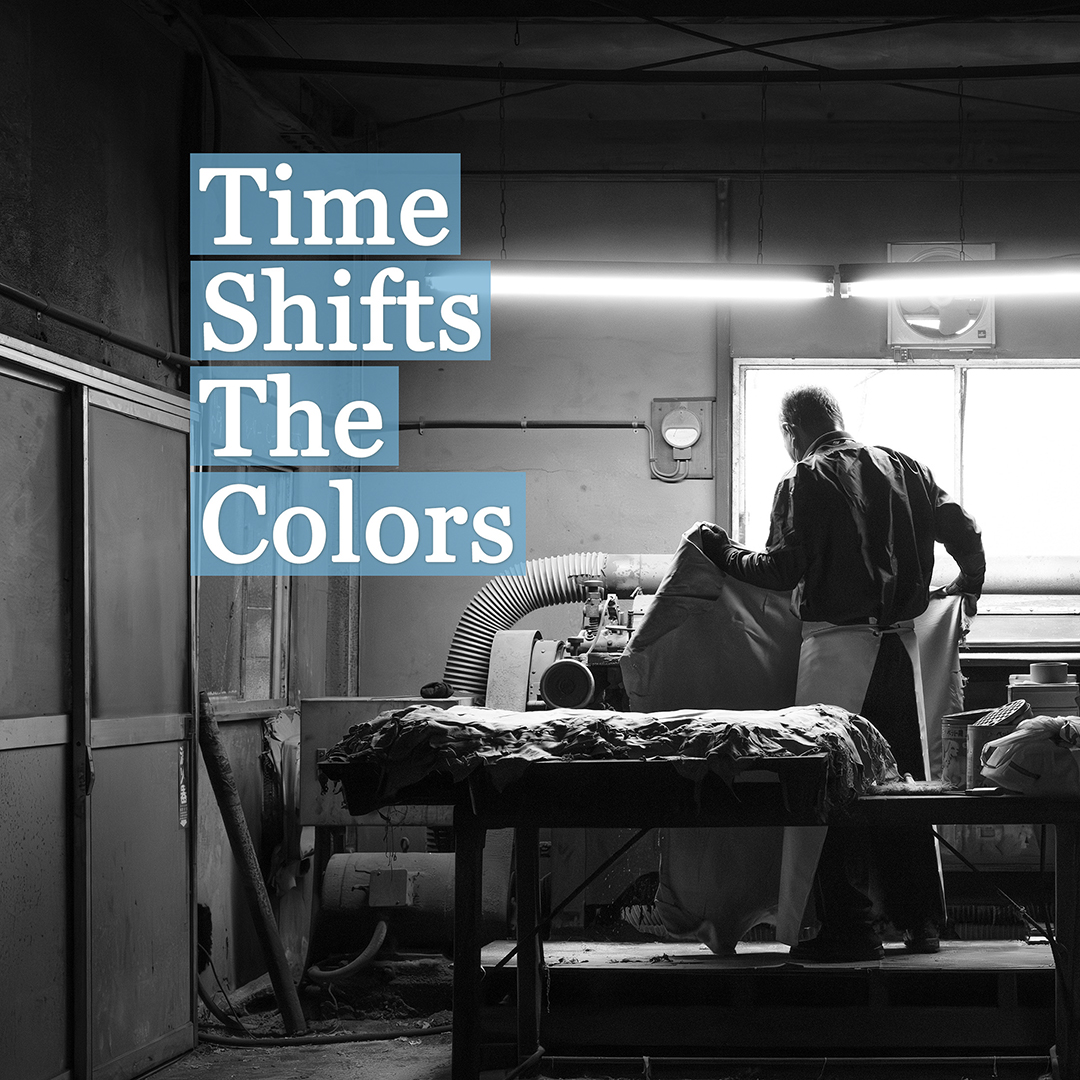 モノクロの写真、革をもって作業する人物。