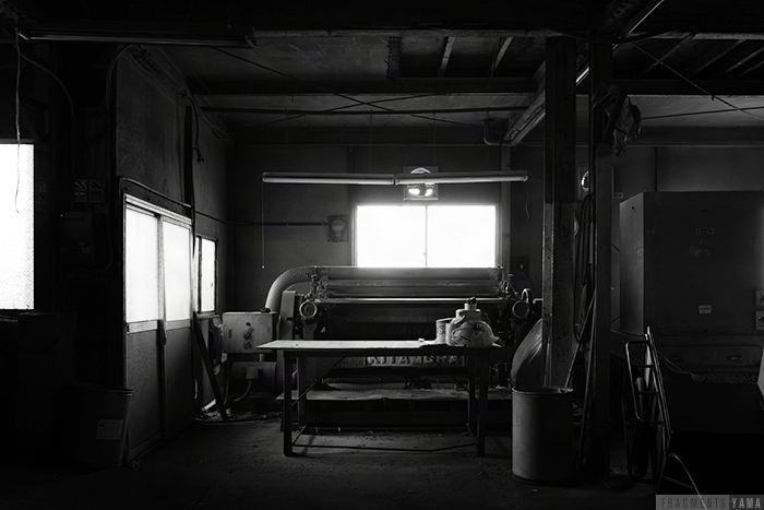 工場内部、機械が置かれている。モノクロ写真