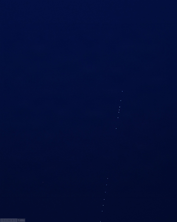 真っ暗な空に、小さな光の点々が一直線に並んでいる