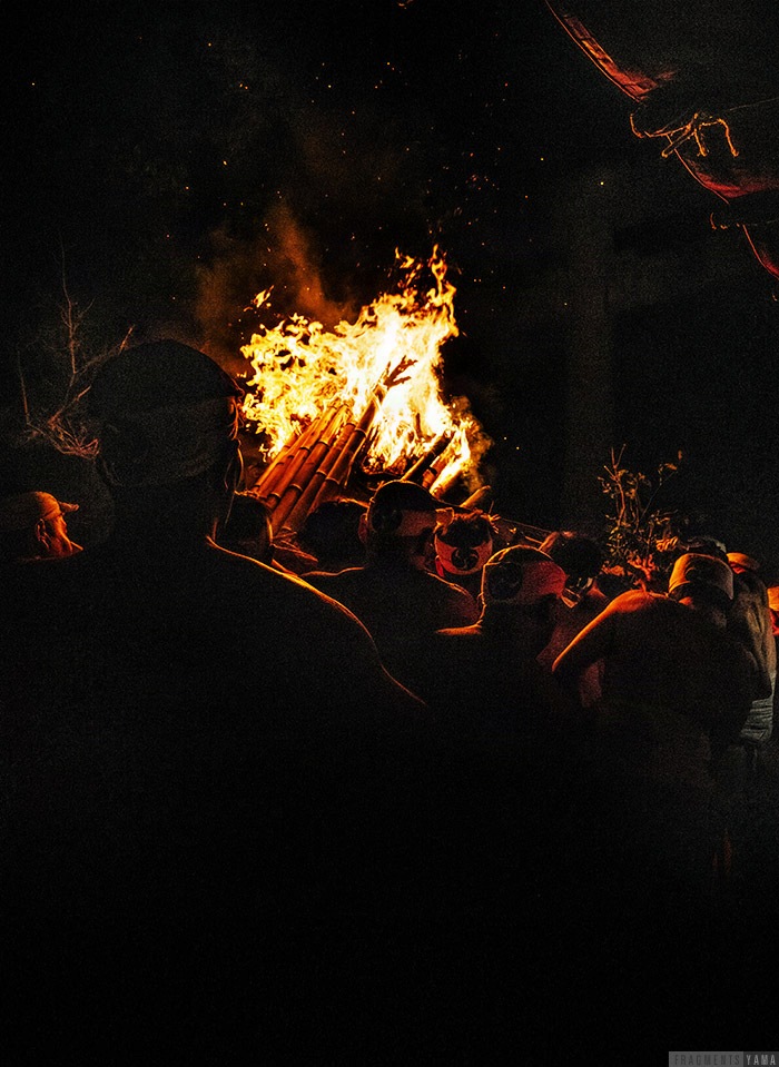 大きな松明を抱えて神社の外に出る男たち