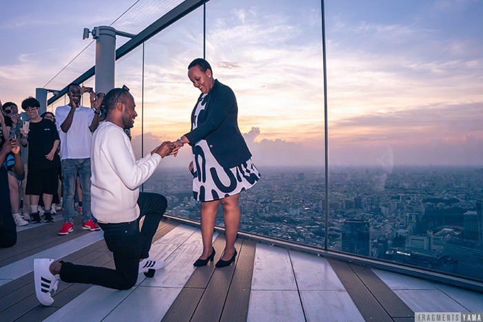 夕日の中、跪いてプロポーズをする男性