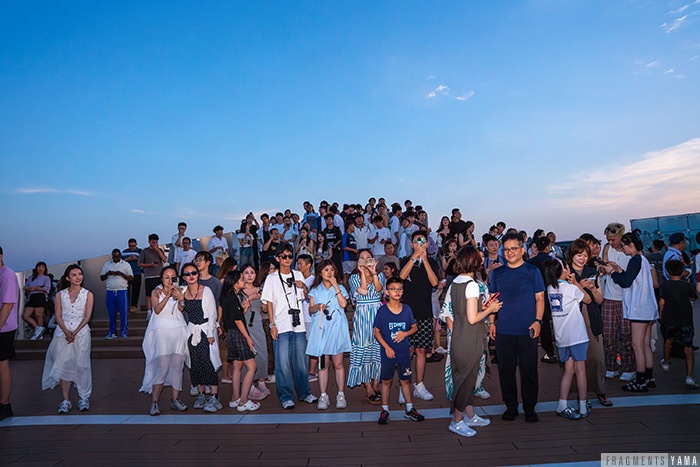 渋谷スカイにいた人たちがプロポーズをする二人の周りに集まっている